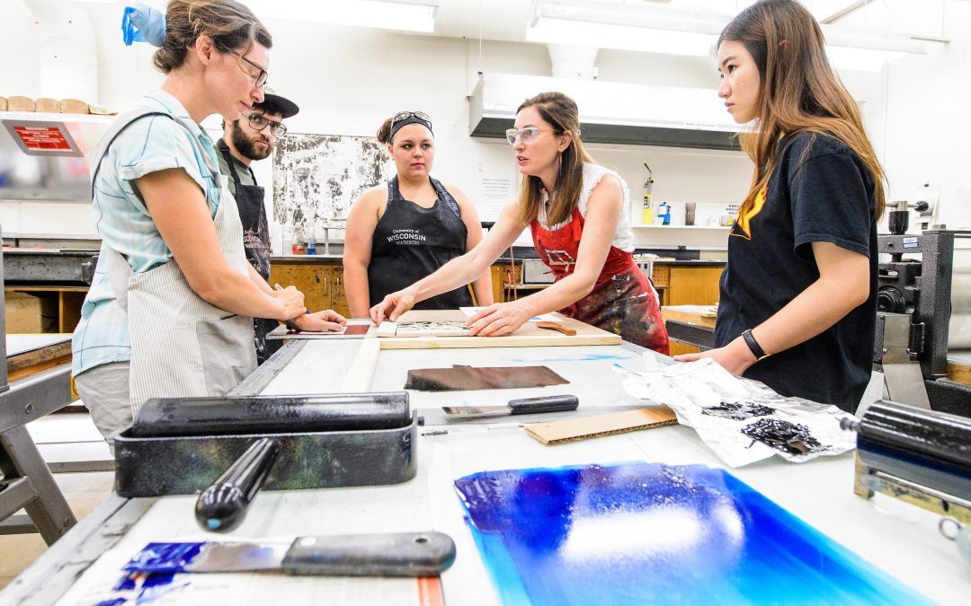 Students work in the printmaking labs in Mosse Humanities Building at the University of Wisconsin-Madison during assistant professor Emily Arthur's (in red apron) Relief Printing course.