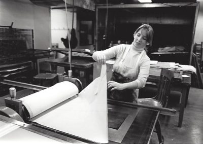 A student pulls a fresh print in a printmaking class.