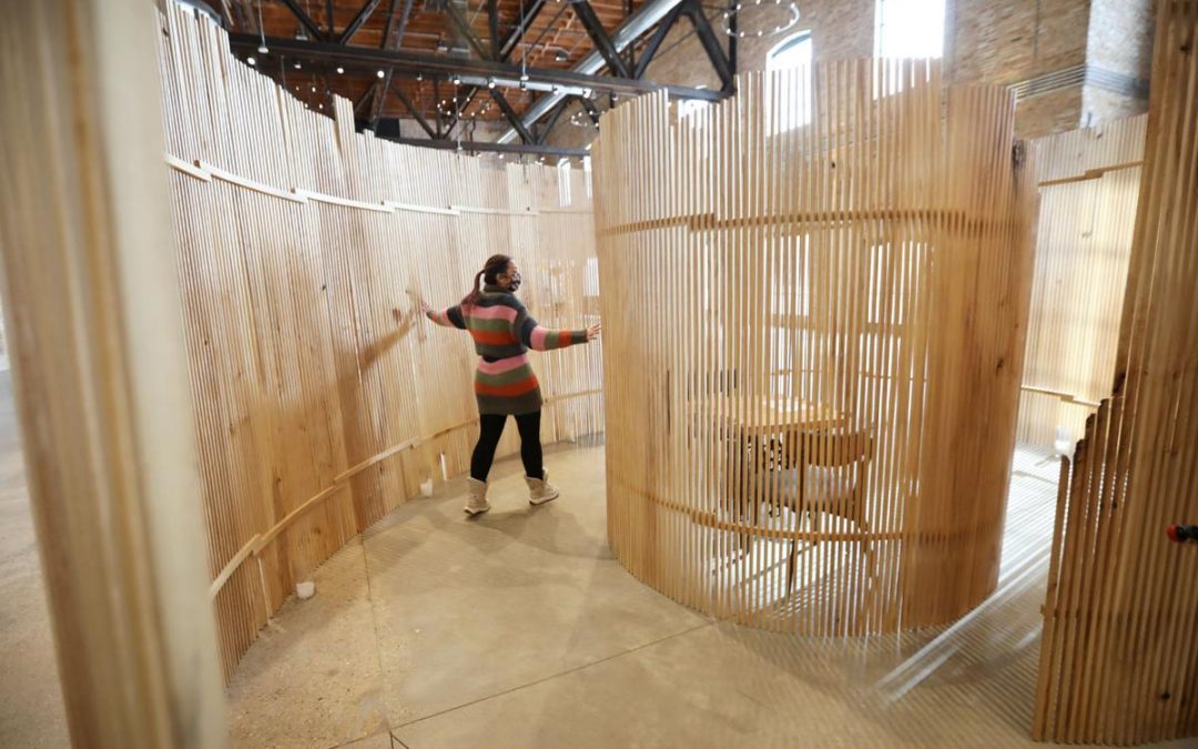 Bethany Jurewicz, director of public programming and business operations with Garver Events at Garver Feed Mill, gives a tour of Matthew Vivirito's work "Withdrawn," made from local ash trees. The piece, part of Winter is Alive! A Cooler World Carnival, includes a two-person table in the middle that can be reserved for a socially distanced, intimate dining experience that includes a four-course meal. Photography by Amber Arnold, State Journal.